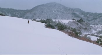 Movie still from “North Korean Partisan in South Korea” (1990), directed by Jeong Ji-yeong – A person is walking up a snowy hill; Extreme Wide shot, High angle