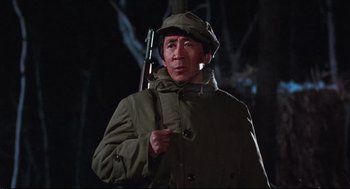 Movie still from “North Korean Partisan in South Korea” (1990), directed by Jeong Ji-yeong – A man holding a rifle wearing a hat and a coat; Medium shot, Low angle