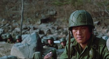 Movie still from “North Korean Partisan in South Korea” (1990), directed by Jeong Ji-yeong – A man wearing a helmet and a green uniform; Close Up shot, Low angle