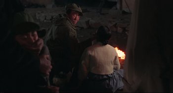 Movie still from “North Korean Partisan in South Korea” (1990), directed by Jeong Ji-yeong – A group of people gathered around a fire; Medium shot, Over the shoulder angle
