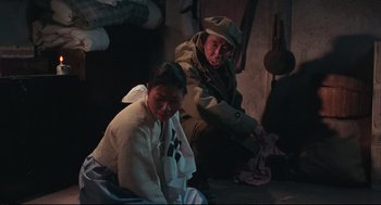 Movie still from “North Korean Partisan in South Korea” (1990), directed by Jeong Ji-yeong – A man and a woman sitting next to each other; Medium shot, High angle