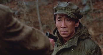 Movie still from “North Korean Partisan in South Korea” (1990), directed by Jeong Ji-yeong – A man in a military uniform with a gun in his hand; Close Up shot, Low angle
