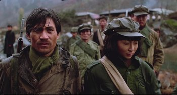 Movie still from “North Korean Partisan in South Korea” (1990), directed by Jeong Ji-yeong – A group of men and women in military fatigues and hats; Medium shot, Over the shoulder angle