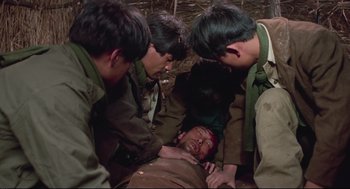 Movie still from “North Korean Partisan in South Korea” (1990), directed by Jeong Ji-yeong – A group of young men standing around an injured man; Medium shot, High angle