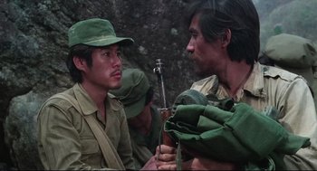 Movie still from “North Korean Partisan in South Korea” (1990), directed by Jeong Ji-yeong – A group of men sitting next to each other on a field; Close Up shot, Over the shoulder angle