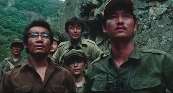 Movie still from “North Korean Partisan in South Korea” (1990), directed by Jeong Ji-yeong – A group of people standing next to each other in the woods; Close Up shot, Low angle