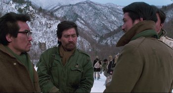 Movie still from “North Korean Partisan in South Korea” (1990), directed by Jeong Ji-yeong – A man in a green jacket talking to another man in a brown jacket; Medium shot, Over the shoulder angle