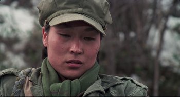 Movie still from “North Korean Partisan in South Korea” (1990), directed by Jeong Ji-yeong – A person wearing a hat and a scarf; Close Up shot, Over the shoulder angle