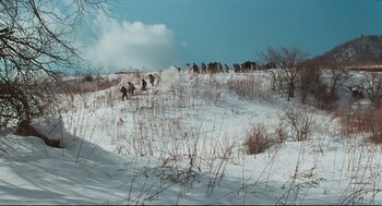 Movie still from “North Korean Partisan in South Korea” (1990), directed by Jeong Ji-yeong – A group of people riding horses through a snowy field; Extreme Wide shot, High angle