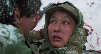 Movie still from “North Korean Partisan in South Korea” (1990), directed by Jeong Ji-yeong – A young person in a green jacket and a man in a green hat; Close Up shot, High angle