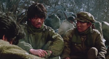 Movie still from “North Korean Partisan in South Korea” (1990), directed by Jeong Ji-yeong – A group of men sitting next to each other in the woods; Medium shot, Low angle
