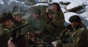 Movie still from “North Korean Partisan in South Korea” (1990), directed by Jeong Ji-yeong – A group of men sitting around a fire; Medium shot, High angle