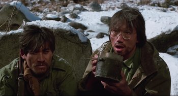 Movie still from “North Korean Partisan in South Korea” (1990), directed by Jeong Ji-yeong – A man holding a cup in his mouth next to another man; Close Up shot, High angle