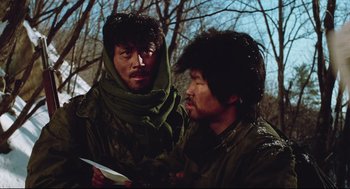 Movie still from “North Korean Partisan in South Korea” (1990), directed by Jeong Ji-yeong – A couple of men standing next to each other in the woods; Medium shot, Low angle