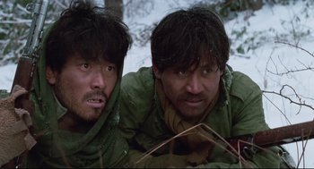 Movie still from “North Korean Partisan in South Korea” (1990), directed by Jeong Ji-yeong – Two men in the snow wearing green shirts and scarves; Close Up shot, Low angle