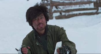 Movie still from “North Korean Partisan in South Korea” (1990), directed by Jeong Ji-yeong – A man in a fur hat is standing in the snow; Medium shot, Low angle