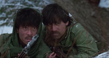 Movie still from “North Korean Partisan in South Korea” (1990), directed by Jeong Ji-yeong – Two men in the woods one is holding a chainsaw; Close Up shot, Low angle