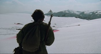 Movie still from “North Korean Partisan in South Korea” (1990), directed by Jeong Ji-yeong – A person holding a stick in a snowy field; Wide shot, High angle