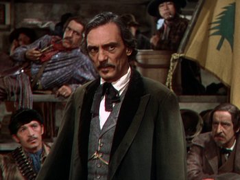 Movie still from “North West Mounted Police” (1940), directed by Cecil B. DeMille – A person wearing a suit and tie; Medium shot, Over the shoulder angle