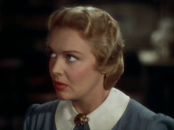 Movie still from “North West Mounted Police” (1940), directed by Cecil B. DeMille – A woman with blonde hair wearing a blue dress; Close Up shot, Over the shoulder angle