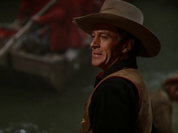 Movie still from “North West Mounted Police” (1940), directed by Cecil B. DeMille – A man wearing a cowboy hat standing in the dark; Close Up shot, Over the shoulder angle