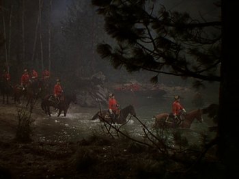 Movie still from “North West Mounted Police” (1940), directed by Cecil B. DeMille – A group of people riding horses across a body of water at night; Extreme Wide shot, High angle