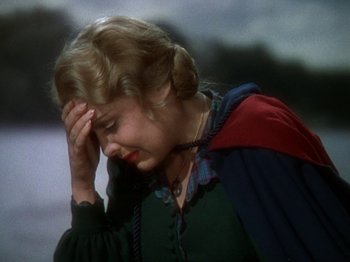 Movie still from “North West Mounted Police” (1940), directed by Cecil B. DeMille – A woman in a green and red dress holding her hand to her face; Close Up shot, Over the shoulder angle