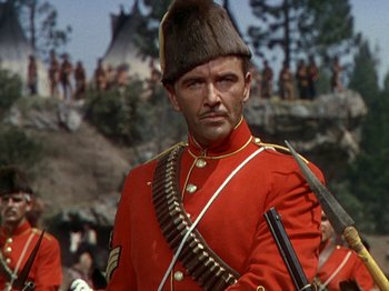 Movie still from “North West Mounted Police” (1940), directed by Cecil B. DeMille – A man in a red military uniform with a rifle; Medium shot, Low angle