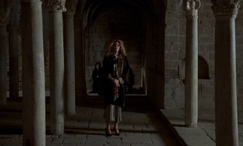 Movie still from “Nostalghia” (1983), directed by Andrei Tarkovsky – A woman standing in an archway in a building; Wide shot, High angle