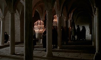 Movie still from “Nostalghia” (1983), directed by Andrei Tarkovsky – A group of people standing in a room with candles; Extreme Wide shot, High angle