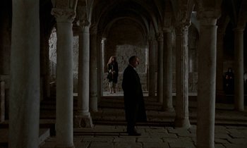 Movie still from “Nostalghia” (1983), directed by Andrei Tarkovsky – A man and a woman standing inside a building; Wide shot, High angle