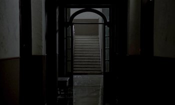 Movie still from “Nostalghia” (1983), directed by Andrei Tarkovsky – An open door leading to a staircase in a building; Extreme Wide shot, High angle