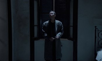 Movie still from “Nostalghia” (1983), directed by Andrei Tarkovsky – A man standing in front of a window in the dark; Wide shot, Low angle