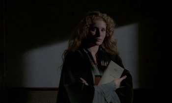 Movie still from “Nostalghia” (1983), directed by Andrei Tarkovsky – A woman with long curly hair is holding a book; Medium shot, Low angle