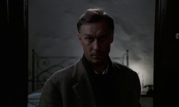 Movie still from “Nostalghia” (1983), directed by Andrei Tarkovsky – A man in a dark room looking at the camera; Close Up shot, Low angle