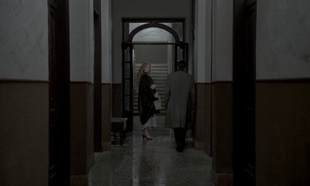 Movie still from “Nostalghia” (1983), directed by Andrei Tarkovsky – A woman and a man walking down a hall way; Wide shot, Over the shoulder angle