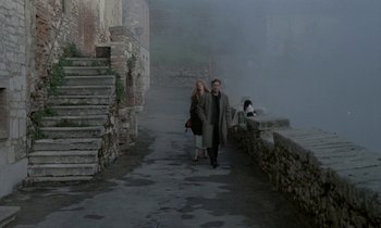 Movie still from “Nostalghia” (1983), directed by Andrei Tarkovsky – A man and a woman walking down a street; Wide shot, High angle