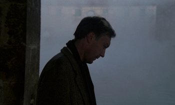 Movie still from “Nostalghia” (1983), directed by Andrei Tarkovsky – A man in a brown jacket is looking down; Medium shot, Over the shoulder angle