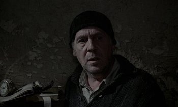 Movie still from “Nostalghia” (1983), directed by Andrei Tarkovsky – A man wearing a black hat and a black jacket; Close Up shot, Over the shoulder angle