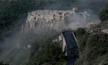 Movie still from “Nostalghia” (1983), directed by Andrei Tarkovsky – A car driving down a road on a mountain side; Extreme Wide shot, High angle