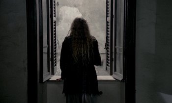 Movie still from “Nostalghia” (1983), directed by Andrei Tarkovsky – A woman standing in front of an open window; Medium shot, Over the shoulder angle