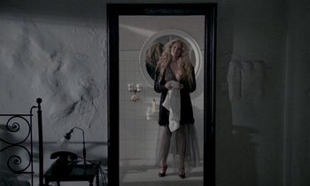 Movie still from “Nostalghia” (1983), directed by Andrei Tarkovsky – A woman standing in front of a mirror in a bathroom; Wide shot, Overhead angle
