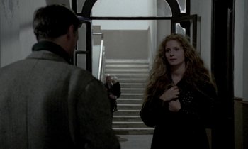 Movie still from “Nostalghia” (1983), directed by Andrei Tarkovsky – A woman standing in front of a man in front of a staircase; Medium shot, Over the shoulder angle