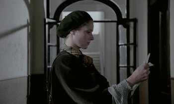 Movie still from “Nostalghia” (1983), directed by Andrei Tarkovsky – A woman in a green hat looking down at her hand; Medium shot, Low angle