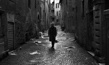 Movie still from “Nostalghia” (1983), directed by Andrei Tarkovsky – A person walking down a street in the rain; Wide shot, Low angle