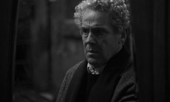 Movie still from “Nostalghia” (1983), directed by Andrei Tarkovsky – Black and white photograph of an older man with curly hair; Close Up shot, Over the shoulder angle