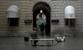 Movie still from “Nostalghia” (1983), directed by Andrei Tarkovsky – A man sitting on top of a bench in front of an archway; Wide shot, High angle