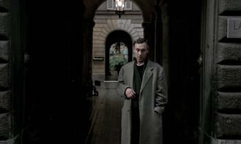 Movie still from “Nostalghia” (1983), directed by Andrei Tarkovsky – A man standing in an archway holding a knife in his hand; Medium shot, Low angle
