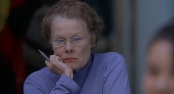 Movie still from “Notes on a Scandal” (2006), directed by Richard Eyre – An older woman with glasses is holding a cigarette in her mouth; Close Up shot, Over the shoulder angle