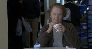 Movie still from “Notes on a Scandal” (2006), directed by Richard Eyre – An older woman sitting at a table drinking a cup of coffee; Close Up shot, Over the shoulder angle